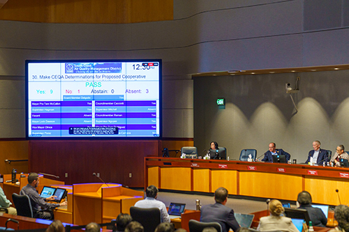 Members of the South Coast Air Quality Management District vote on the Cooperative Agreement – results of the vote are posted on a large screen as the audience and board look on